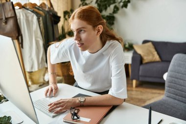 A young man intensely concentrates on tasks while seated at a chic workspace, surrounded by decor. clipart