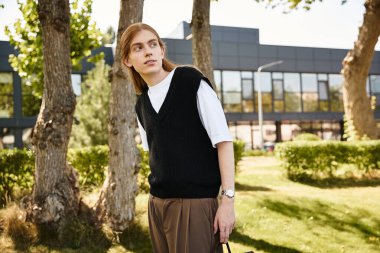 Düşünceli bir suratı olan genç bir adam huzur dolu bir parkta gezintiden zevk alıyor..