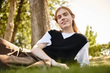 A young man lounges peacefully in the grass, enjoying the warmth of a sunny afternoon. clipart