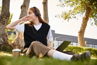 Dışarıda dinlenirken, genç bir adam müzik, dizüstü bilgisayar ve yeşilliğin ortasında kahve ile gevşiyor..