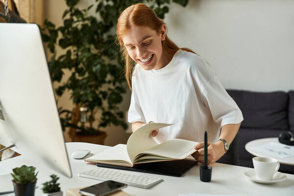 Молодой человек улыбается, наслаждаясь книгой в своем ярком и творческом рабочем пространстве.