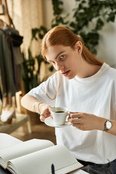 Молодой человек вдумчиво пьет кофе, изучая ноты в расслабляющей обстановке..