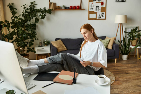 A young man sits back with his feet on a table, thoughtfully examining papers in a stylish home.