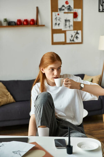 Relaxing at home, a young man enjoys his coffee in a stylish, comfortable space.