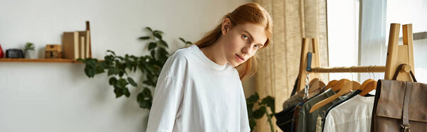 A young man stands in a cozy space, exuding confidence while showcasing modern fashion.