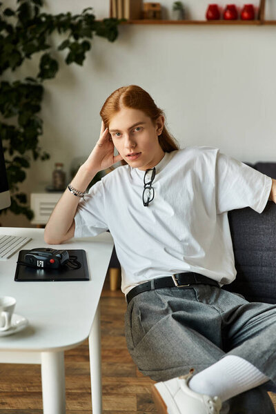 Молодой человек сидит небрежно, положив голову на руку, размышляя о своем рабочем месте..