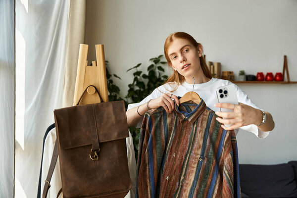 Молодой человек держит разноцветную полосатую рубашку, делая селфи дома.