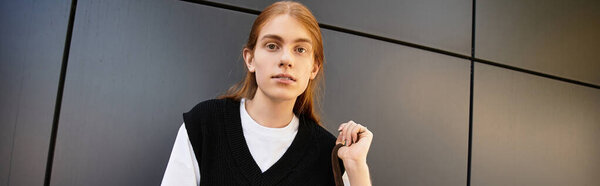 Молодой человек стоит на гладком, современном фоне, демонстрируя свой уникальный стиль.