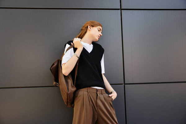 Молодой человек в модном наряде стоит небрежно, излучая уверенность в модной обстановке.