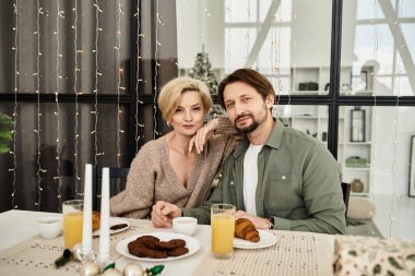 A couple sits close at their table sharing breakfast and joy in a cozy, warmly lit space. clipart