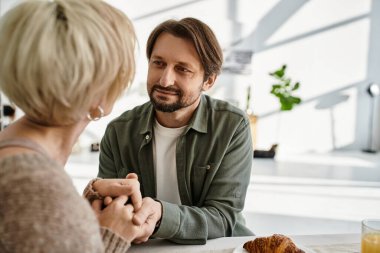 Bir çift sıcak evlerinde kahvaltıda el ele tutuşurken samimi bir konuşma yapıyor..