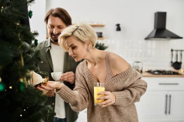 Sevgi dolu bir çift Noel ağacını süs ve tatil neşesiyle süslemekten zevk alır..