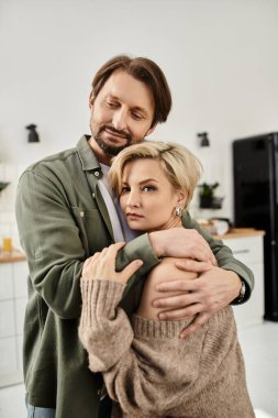 A couple embraces tenderly in their kitchen, enjoying a quiet, intimate moment together. clipart