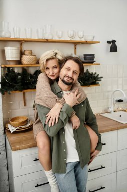 Sıcak ve davetkar bir mutfak atmosferiyle çevrili bir çift sevgi dolu bir kucaklaşmanın tadını çıkarıyor..