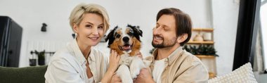 Neşeli bir çift, sıcak, sıcak bir evde neşeli bir köpekle birlikte vakit geçirmeyi sever.