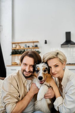 Mutlu bir çift köpekleriyle sarılıp evde sıcak bir anın tadını çıkarıyor..