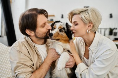 Bir çift evde huzurlu bir anın tadını çıkarırken köpeğini mutlu bir şekilde kucaklıyor..