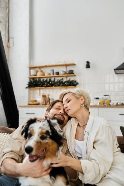 Çiftler kanepede köpeklerine sevgi dolu bir şekilde sarılmaktan hoşlanırlar..