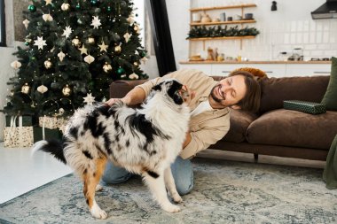 Attractive man playing with his dog. clipart