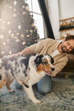 Yakışıklı adam evde köpeğiyle oynuyor..