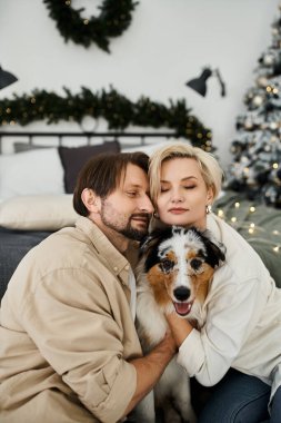 Çift, güzel dekore edilmiş bir oturma odasında köpeklerine sarılırken sıcak bir anı paylaşıyor..