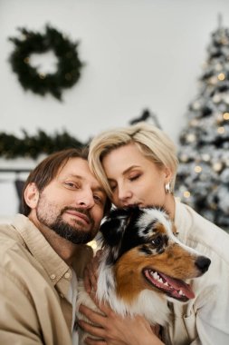 Bir çift, tatil sezonunda evde sıcak bir anın tadını çıkararak köpeklerini kucaklıyor..