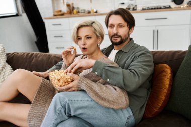 Bir çift rahat bir akşamın tadını çıkarır, patlamış mısır ve kahkahaları rahat koltuklarında paylaşırlar..