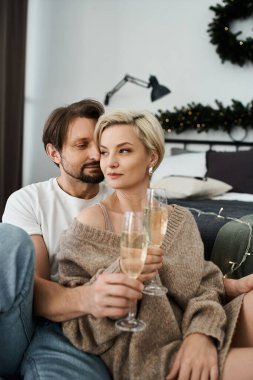 Sıcak bir anı paylaşan bir çift, sıcak evlerinde şampanyayla eğleniyor..