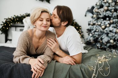 Sevgi dolu bir çift, bayram süslemeleriyle şenlikli bir yatakta tatlı bir kucaklaşmanın tadını çıkarır..