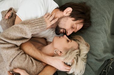 Yumuşak bir kanepede uzanmış sıcaklığı ve sevgiyi paylaşan bir çift şefkatli bir kucaklaşmanın tadını çıkarır..