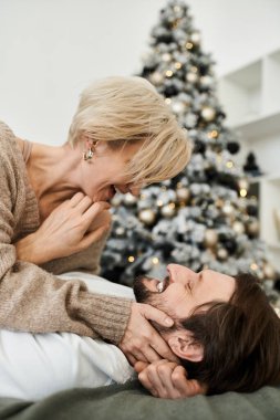 Sevgi dolu bir çift, evde neşeli bir anın tadını çıkarır. Noel ruhuyla sarılıp güler..