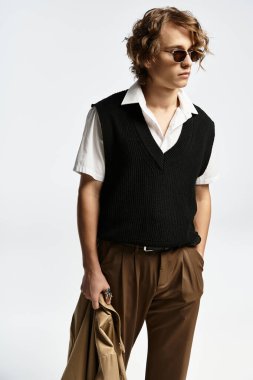 Şık giyinmiş yakışıklı bir genç, kendine güvenen bir şekilde bir stüdyoda poz veriyor, sonbahar modasının zarafetini somutlaştırıyor..