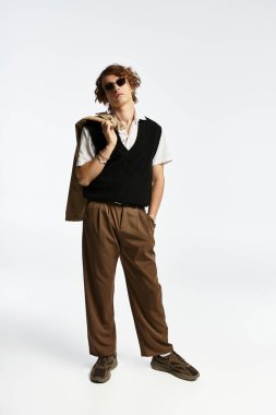 Şık bir genç, modern bir stüdyo ortamında kendine güvenen, sofistike bir sonbahar kıyafeti sergiliyor..