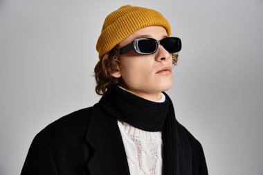 Tarz sahibi genç bir adam, siyah bir ceket ve sarı bir bereyle modern moda havası yayıyor..