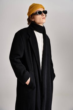 Göz alıcı genç bir adam şık siyah bir ceket ve parlak sarı bir bereyle moda anlayışını sergiliyor..