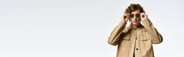 A handsome young man with wavy hair presents a refined autumn look in an artistic studio environment.