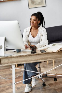 Genç ve güzel bir kadın, çalışma materyallerini incelerken rahat ofisinden özenle çalışıyor..