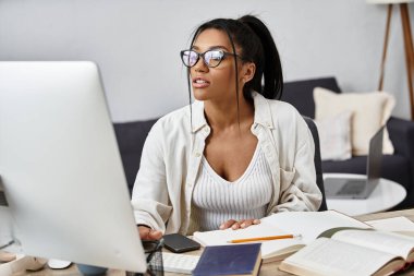 A young woman studies intently at her home desk, surrounded by books and notes. clipart