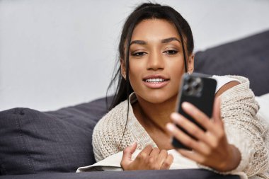 Bu kadın mutlu bir şekilde evden ders çalışıyor, akıllı telefonunu internet derslerine bağlanmak için kullanıyor..