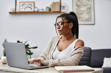 A beautiful young woman is engaged in remote learning, tapping away on her laptop at home. clipart