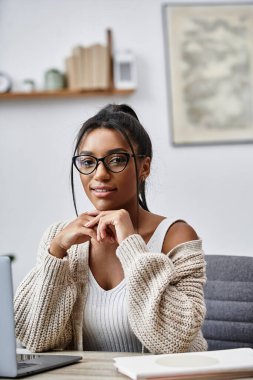 A beautiful young woman studies intently at her home desk, surrounded by a comfortable atmosphere. clipart