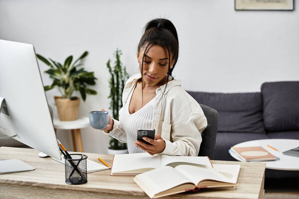 Молодая женщина занимается дистанционным исследованием, держит кофе и сосредоточена на телефоне и книгах..