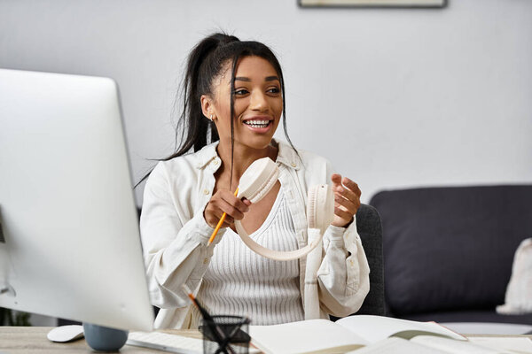 Молодая женщина улыбается, когда учится удаленно с помощью ноутбука и наушников.