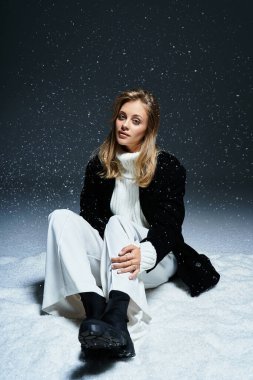 A beautiful young woman sits in the snow, embodying winters tranquility with elegance and grace.