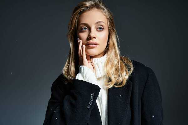A young woman stands gracefully, showcasing winter fashion with a contemplative look in her eyes.