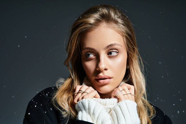Молодая красивая женщина обнимает тепло, в то время как снежинки мягко падают вокруг нее.