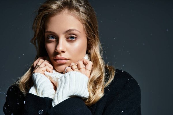 Красивая молодая женщина обнимает холод, ее выражение созерцательное и спокойное в зимнем наряде.