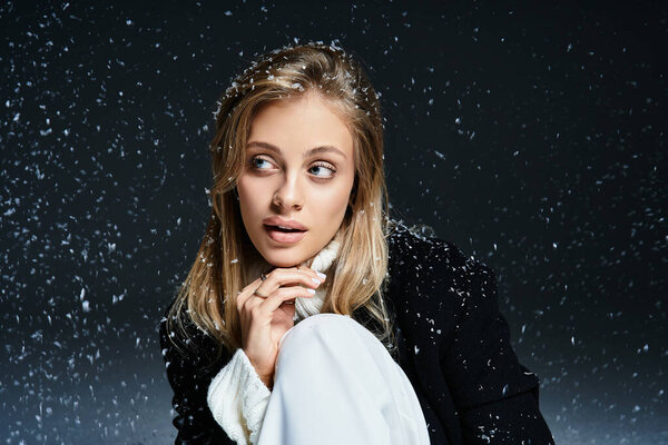 A beautiful young woman gazes thoughtfully as snow gently falls around her in the dark.