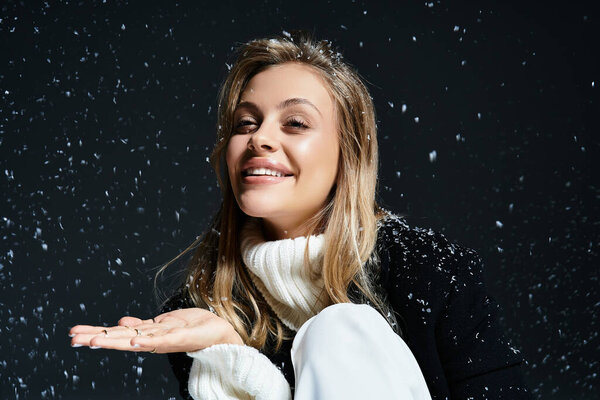 A cheerful young woman sits gracefully, catching snowflakes with sparkling eyes and a warm smile.