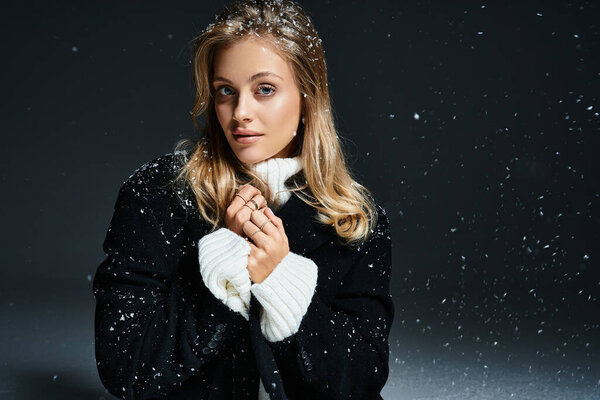 A young woman stands gracefully, adorned in warm clothing as snowflakes softly fall around her.